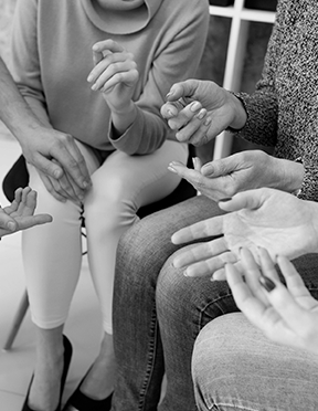 Групповая терапия: участники сидят в кругу, протягивая руки к центру в знак поддержки